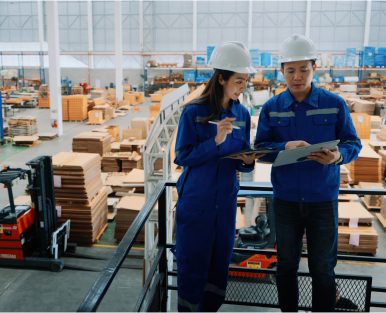 Workers reviewing documents in warehouse setting.
